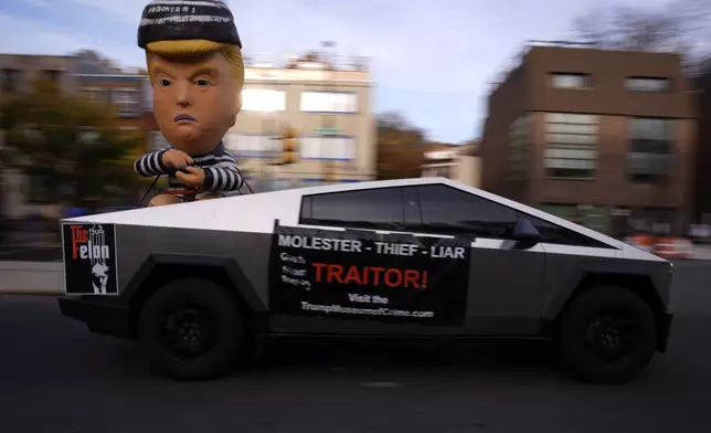 A Tesla Cybertruck with a figure of Republican presidential nominee former President Donald Trump and signs attached is pictured before a campaign rally for Democratic presidential nominee Vice President Kamala Harris outside the Philadelphia Museum of Art, Monday, Nov. 4, 2024, in Philadelphia. (AP Photo/Matt Rourke)