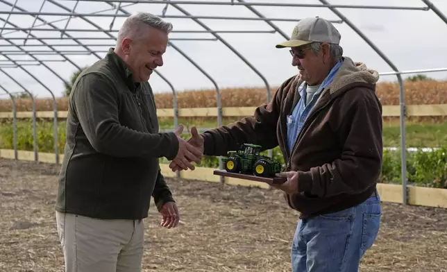 Congressman Eric Sorensen, left, receives an award in recognition of the endorsement from Denny Van Daele during joining Rock Island County farmers and Illinois Farm Bureau leaders at a family farm in Taylor Ridge, Ill., Monday, Oct. 14, 2024. He discussed the status of the farm bill, the effects of severe weather on farms, and Sorensen's efforts on behalf of Illinois producers. (AP Photo/Nam Y. Huh)