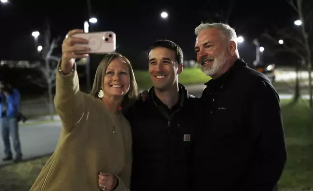 Republican congressional candidate Austin Theriault, center, poses for a photo with supporters Tuesday, Nov. 5, 2024 outside the Cross Insurance Center in Bangor, Maine. (AP Photo/Joel Page)