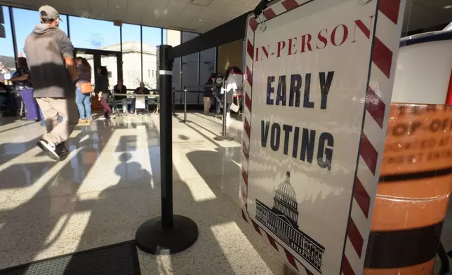 A person walks past a sign during early voting in the general election, Friday, Nov. 1, 2024, in Fall River, Mass. (AP Photo/Steven Senne)