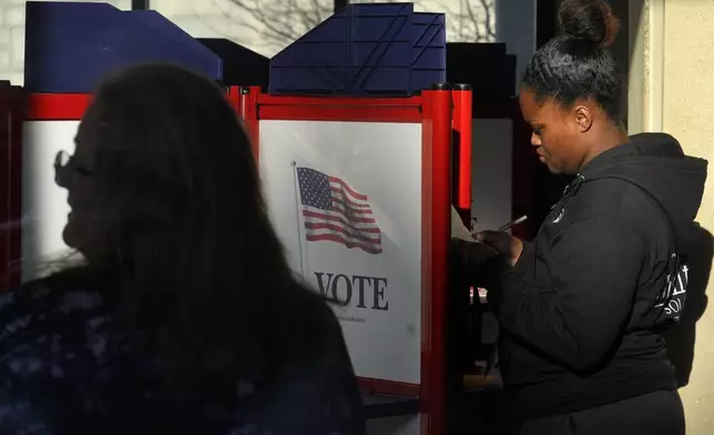 A voter, right, fills out their their ballot during early voting in the general election, Friday, Nov. 1, 2024, in Fall River, Mass. (AP Photo/Steven Senne)