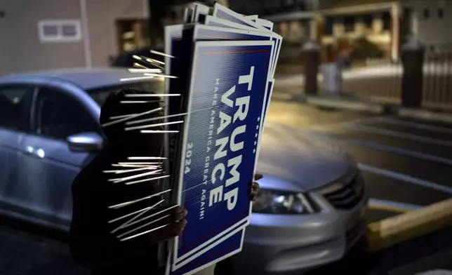 Arif Armanjisan helps carry yard signs into a campaign office for Republican presidential nominee former President Donald Trump, Monday, Nov. 4, 2024, in Hamtramck, Mich. (AP Photo/David Goldman)