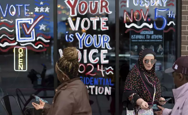 Chelsey Salama, right, hands out fliers while volunteering with the Abandon Harris movement encouraging voters to choose Green Party presidential candidate Jill Stein, Monday, Nov. 4, 2024, in Dearborn, Mich. (AP Photo/David Goldman)