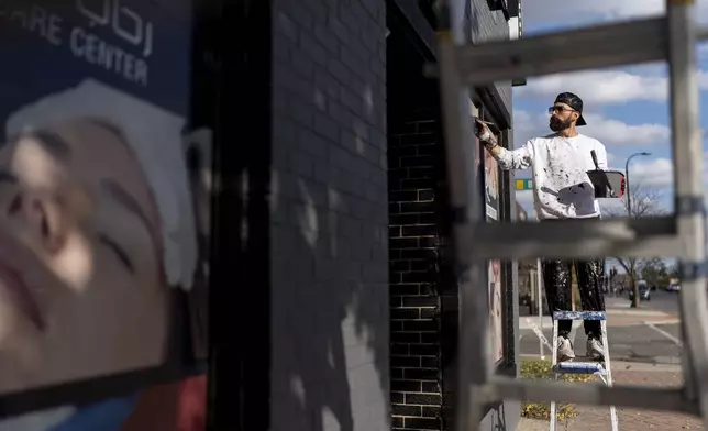 Adam Hameed, paints the exterior of a skin care center, Wednesday, Nov. 6, 2024, in Dearborn, Mich, the nation's largest Arab-majority city. "For me I worry about my kids and the economy. Everything's too expensive and I can't buy what I want for my kids," said Hameed who voted for President-elect Donald Trump. "I want my kids to see me strong and doing well." (AP Photo/David Goldman)