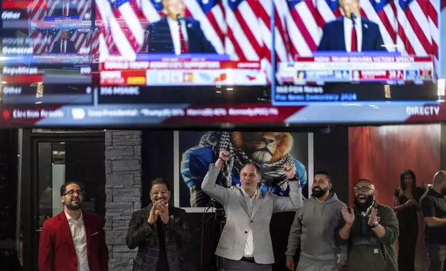 From left, Paul Manni, Sam Alasri, Wasel Yousaf, Waseem Makani and Abrahim Tamimi, cheer as Republican presidential nominee former President Donald Trump's speech is broadcast during an Arab Americans for Trump watch party at the Lava Java Cafe, a hookah lounge, in the early hours of Wednesday, Nov. 6, 2024, in Dearborn, Mich. (AP Photo/David Goldman)