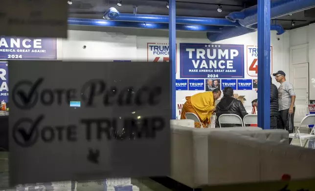 A sign hangs in the window as volunteers meet in the campaign office for Republican presidential nominee former President Donald Trump, Monday, Nov. 4, 2024, in Hamtramck, Mich. (AP Photo/David Goldman)