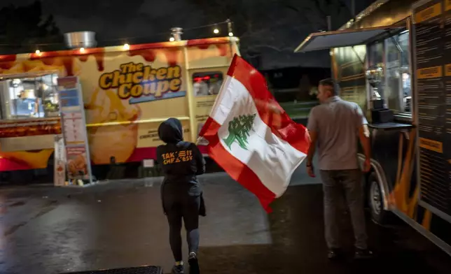 Ameera Amad waves the Lebanese flag outside an American Muslims and Allies election night watch party Tuesday, Nov. 5, 2024, in Dearborn, Mich., the nation's largest Arab-majority city. (AP Photo/David Goldman)