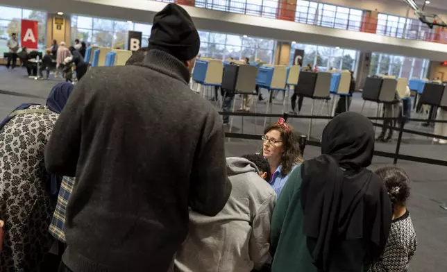 An election official helps check in voters at Ford Community and Performing Arts Center on the last day of early in-person voting, Sunday, Nov. 3, 2024, in Dearborn, Mich., the nation's largest Arab-majority city. (AP Photo/David Goldman)