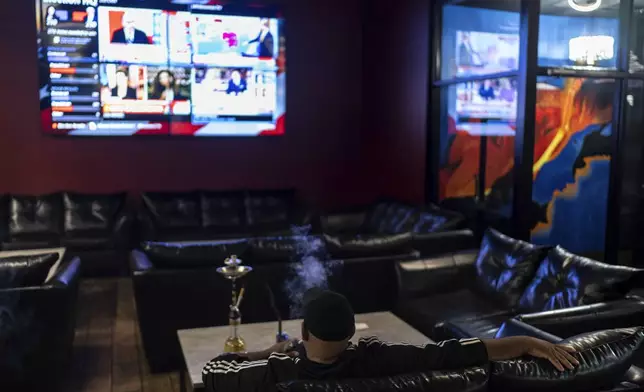 A supporter of Republican presidential nominee former President Donald Trump watches election results at an Arab Americans for Trump watch party at the Lava Java Cafe, a hookah lounge, in the early hours of Wednesday, Nov. 6, 2024, in Dearborn, Mich. (AP Photo/David Goldman)