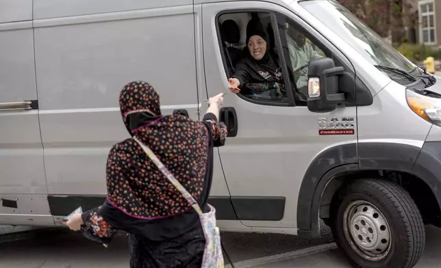 Chelsey Salama, left, with the Abandon Harris movement, hands out a flyer to passing motorists encouraging them to vote for Green Party presidential candidate Jill Stein, Monday, Nov. 4, 2024, in Dearborn, Mich., the nation's largest Arab-majority city. (AP Photo/David Goldman)