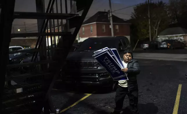 Arif Armanjisan helps carry yard signs into a campaign office for Republican presidential nominee former President Donald Trump the night before the general election Monday, Nov. 4, 2024, in Hamtramck, Mich. (AP Photo/David Goldman)