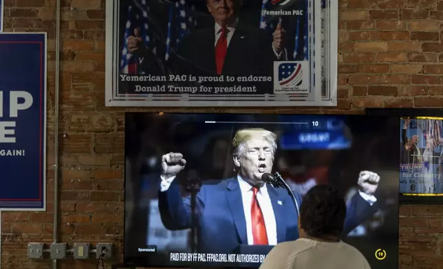 Arif Armanjisan watches an advertisement for Republican presidential nominee former President Donald Trump at his campaign office the night before the general election Monday, Nov. 4, 2024, in Hamtramck, Mich. (AP Photo/David Goldman)