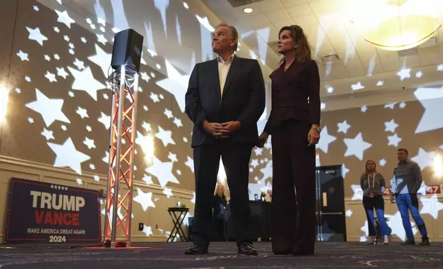 Republican Michigan Senate candidate Mike Rogers, left, and his wife, Kristi Clemens Rogers, right, look up at screens during an election night watch party, Tuesday, Nov. 5, 2024, at Suburban Showplace Collection in Novi, Mich. (AP Photo/Paul Sancya)