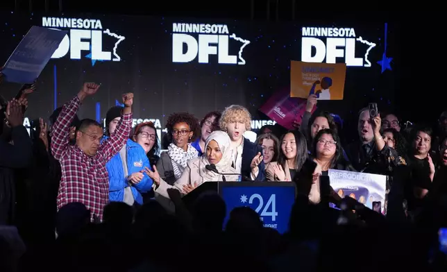 Rep. Ilhan Omar, center, acknowledges attorney general Keith Ellison, left, while speaking at the DFL election night watch party, Tuesday, Nov. 5, 2024, in St. Paul, Minn. (AP Photo/Abbie Parr)