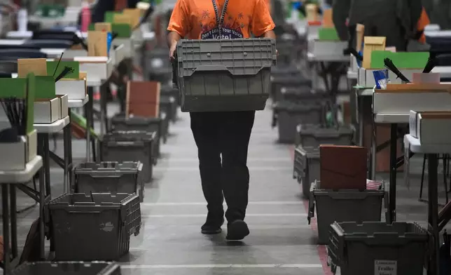 A county worker carries a box in the extraction and inspection area at the Clark County Election Department, Saturday, Nov. 2, 2024, in North Las Vegas, Nev. (AP Photo/John Locher)