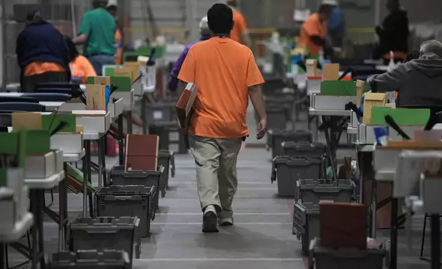 A county worker carries a folder of ballots in the extraction and inspection area at the Clark County Election Department, Saturday, Nov. 2, 2024, in North Las Vegas, Nev. (AP Photo/John Locher)