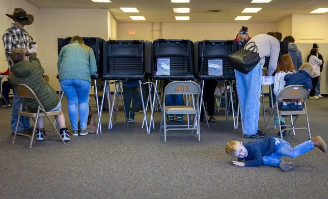 Joey Ferno, 4, plays on the floor while his mother Whitney, top, casts her ballot at the Your Vote Center in Petroglyph Plaza on Election Day, Tuesday, Nov. 5, 2024, in Albuquerque, N.M. (Gino Gutierrez/The Albuquerque Journal via AP)