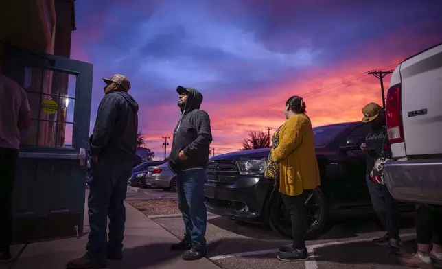 Daniel Barth, 38, center, waits in line to cast his vote on Election Day at the Bernalillo County Visitor Center while the sunsets in the South Valley of Albuquerque, N.M., on Tuesday, Nov. 5, 2024. (Chancey Bush/The Albuquerque Journal via AP)