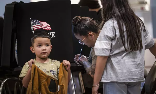 Kassandra Varela casts her vote on Election Day while her 4-year-old son, Apollo, waits by her side at the Bernalillo County Visitor Center in Albuquerque, N.M., on Tuesday, Nov. 5, 2024. (Chancey Bush/The Albuquerque Journal via AP)