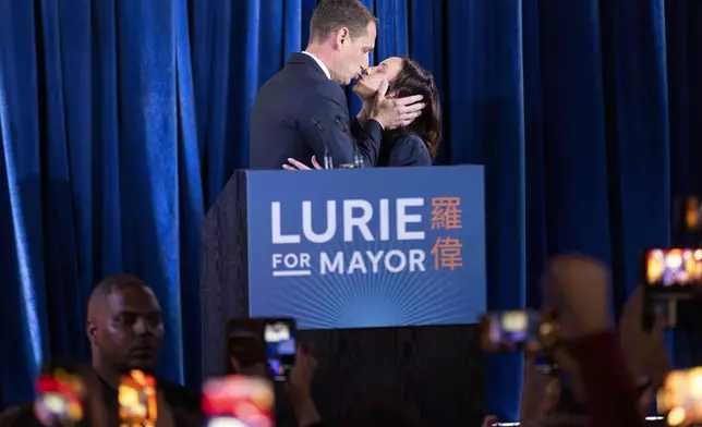 Mayoral candidate Daniel Lurie, center left, kisses his spouse Becca Prowda, center right, during his election night watch party at The Chapel in San Francisco, Tuesday, Nov. 5, 2024. (Santiago Mejia/San Francisco Chronicle via AP)ca