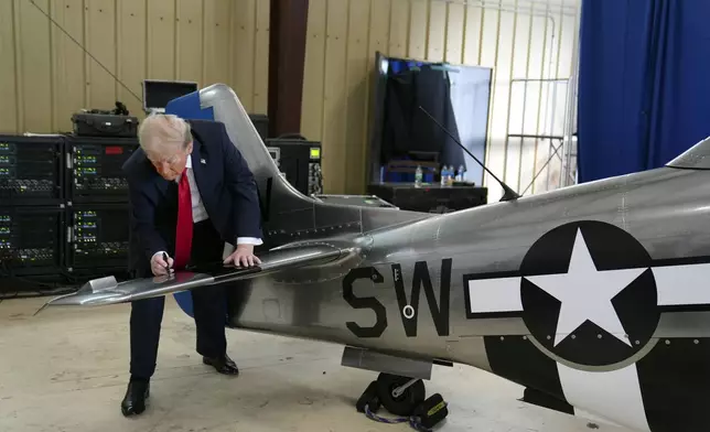 Republican presidential nominee former President Donald Trump autographs a plane before he speaks at a campaign rally at Gastonia Municipal Airport, Saturday, Nov. 2, 2024, in Gastonia, N.C. (AP Photo/Evan Vucci)