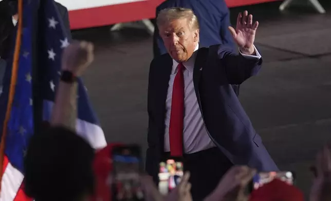 Republican presidential nominee former President Donald Trump waves as he departs a campaign rally at Van Andel Arena, Tuesday, Nov. 5, 2024, in Grand Rapids, Mich. (AP Photo/Paul Sancya)