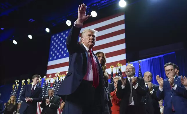 Republican presidential nominee former President Donald Trump waves as he walks with former first lady Melania Trump at an election night watch party at the Palm Beach Convention Center, Wednesday, Nov. 6, 2024, in West Palm Beach, Fla. (AP Photo/Evan Vucci)