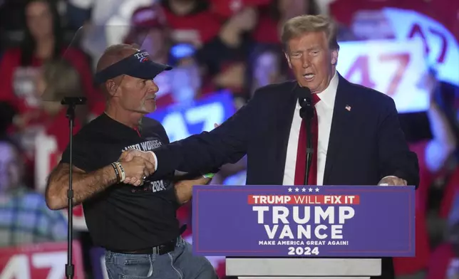 Republican presidential nominee former President Donald Trump shakes hands with Brian Pannebecker as he speaks at a campaign rally at Macomb Community College Friday, Nov. 1, 2024, in Warren, Mich. (AP Photo/Paul Sancya)