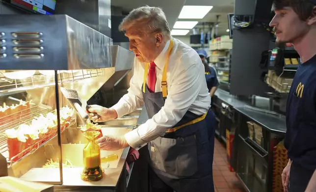 Republican presidential nominee former President Donald Trump serves french fries as an employee looks on during a visit to McDonald's in Feasterville-Trevose, Pa., Sunday, Oct. 20, 2024. (Doug Mills/The New York Times via AP, Pool)