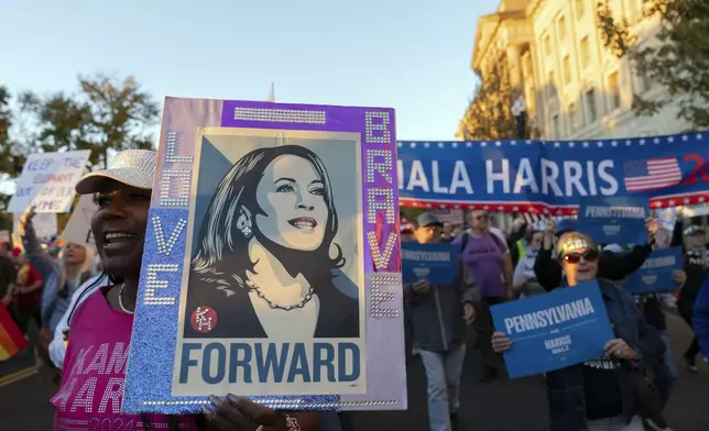 Demonstrator hold up their banner as they march to the White House during the Women's March rally in Washington, Saturday, Nov. 2, 2024. (AP Photo/Jose Luis Magana)