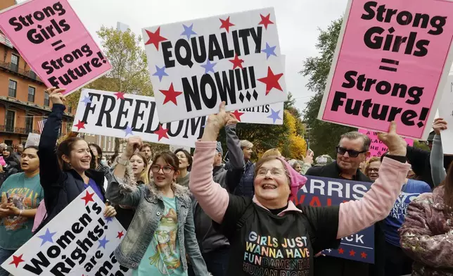 Marji Roy, foreground right, of Ashford, Conn., holds signs during the National Women's March, Saturday, Nov. 2, 2024, in Boston. (AP Photo/Michael Dwyer)