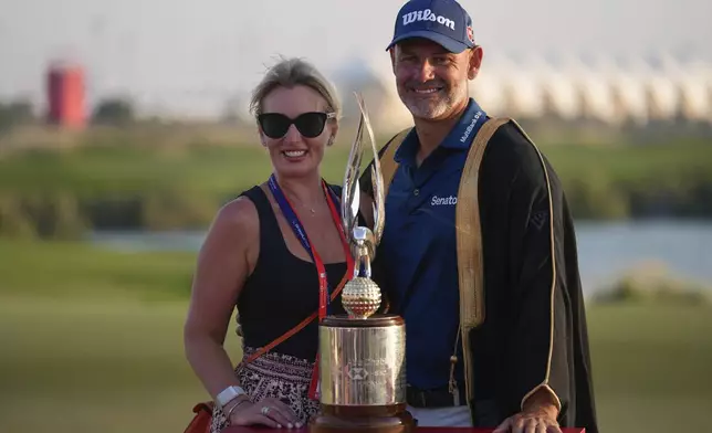 Paul Waring and his wife pose with the trophy during the awards ceremony after winning the Abu Dhabi Golf Championship in Abu Dhabi, United Arab Emirates, Sunday, Nov. 10, 2024. (AP Photo/Altaf Qadri)