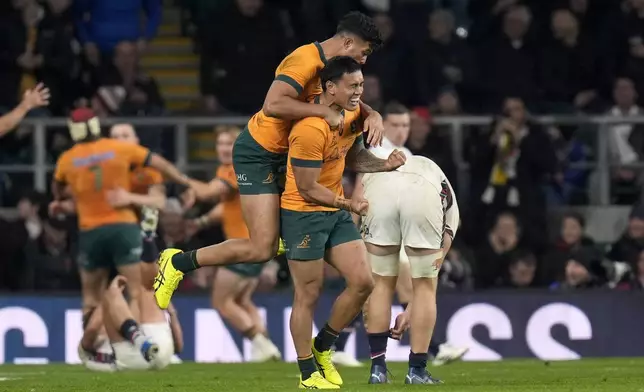 Australia's Len Ikitau, right, and Joseph Suaalii celebrate after team-mate Max Jorgensen, not in photo, scored a try during the Autumn Nations series rugby union match between England and Australia, at Twickenham stadium, London Saturday, Nov. 9, 2024. (David Davies/PA via AP)