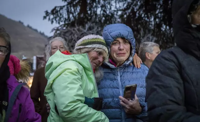 Trina Gioshes comforts Mari Auman as they mourn the loss of grizzly bear No. 399 during a candlelight vigil in Jackson, Wyo., Saturday, Nov. 2, 2024. (AP Photo/Amber Baesler)