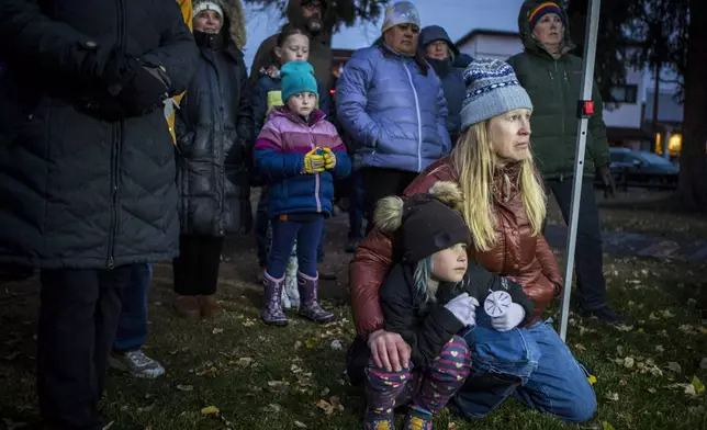 Rae Smith, 6, and her mother Leigh Reagan Smith listen to speakers at a candlelight vigil for grizzly bear No. 399 in Jackson, Wyo., Saturday, Nov. 2, 2024. (AP Photo/Amber Baesler)
