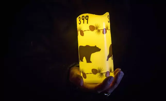 Catherina Gallegos holds a decorated candle in memory of grizzly bear No. 399 at a candlelight vigil in Jackson, Wyo. on Nov. 2, 2024. (AP Photo/Amber Baesler)