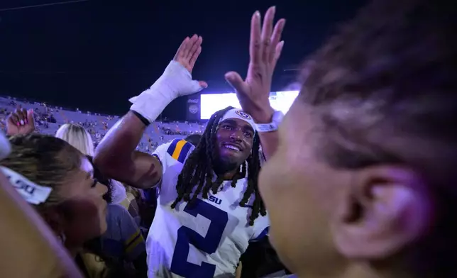 FILE - LSU safety Jardin Gilbert (2) celebrates with fans after they rushed the field after the team's overtime victory against Mississippi in an NCAA college football game in Baton Rouge, La., Saturday, Oct. 12, 2024. (AP Photo/Matthew Hinton, File)