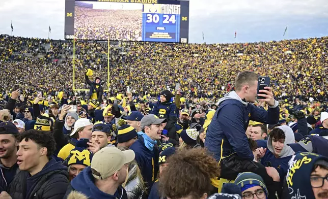 FILE - Fans rush the field after Michigan defeated Ohio State 30-24 in an NCAA college football game, Saturday, Nov. 25, 2023, in Ann Arbor, Mich. (AP Photo/David Dermer)