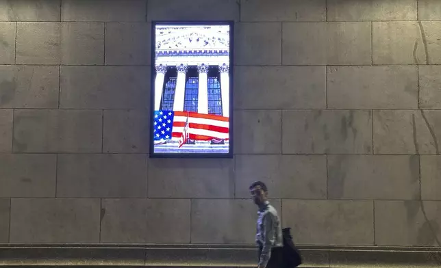 A man passes a video monitor on the side of the New York Stock Exchange in New York's Financial District on Tuesday, Nov. 5, 2024. (AP Photo/Peter Morgan)