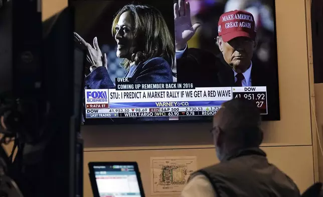 A screen on the floor of the New York Stock Exchange, Monday, Nov. 4, 2024 shows a broadcast talking about Kamala Harris and Donald Trump. (AP Photo/Richard Drew)