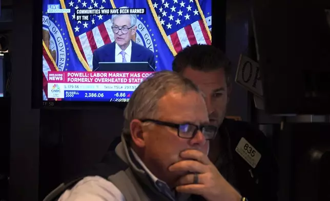A pair of traders work on the floor of the New York Stock Exchange, Thursday, Nov. 7, 2024, in New York, as Federal Reserve Chair Jerome Powell news conference in Washington is displayed on a monitor. (AP Photo/Richard Drew)