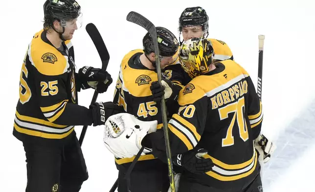 Boston Bruins defenseman Brandon Carlo (25) left wing Cole Koepke (45) defenseman Charlie McAvoy (73) celebrate with goaltender Joonas Korpisalo (70) after beating the Calgary Flames in overtime of an NHL hockey game, Thursday, Nov. 7, 2024, in Boston. (AP Photo/Steven Senne)