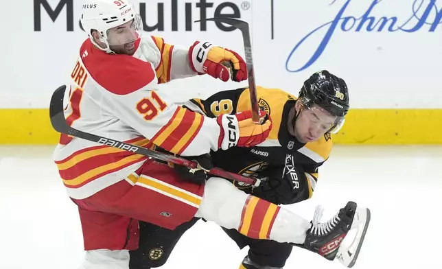 Calgary Flames center Nazem Kadri (91) and Boston Bruins center Tyler Johnson (90) collide in the third period of an NHL hockey game, Thursday, Nov. 7, 2024, in Boston. (AP Photo/Steven Senne)