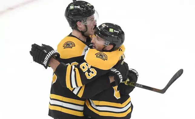 Boston Bruins left wing Brad Marchand, right, celebrates his goal with defenseman Charlie McAvoy, left, after scoring in overtime to end an NHL hockey game against the Calgary Flames, Thursday, Nov. 7, 2024, in Boston. (AP Photo/Steven Senne)