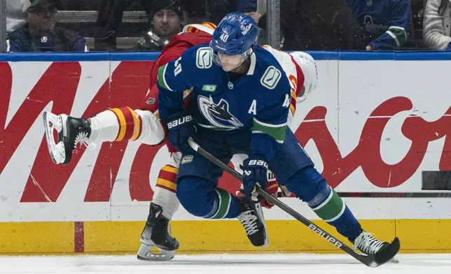 Vancouver Canucks' Elias Pettersson, front, hits Calgary Flames' MacKenzie Weegar during first period of an NHL hockey game in Vancouver, B.C., Tuesday, Nov. 12, 2024. (Rich Lam/The Canadian Press via AP)