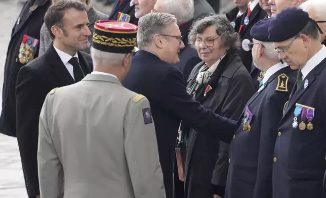 French President Emmanuel Macron, left, and British Prime Minister Keir Starmer, center, meet veterans during ceremonies marking the 106th anniversary of the Armistice, a celebration of their countries' friendship, as nations across the world pay tribute to their fallen soldiers in World War I, Monday, Nov. 11, 2024 in Paris, (AP Photo/Michel Euler, Pool)