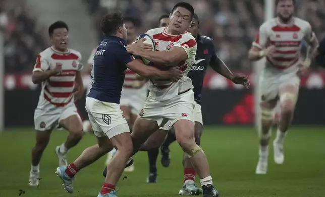 Japan's Shuhei Takeuchi, center, is tackled by France's Antoine Dupont during the Autumn Nations series rugby union match between France and Japan at the Stade de France in Saint-Denis, outside Paris, Saturday, Nov. 9, 2024. (AP Photo/Christophe Ena)