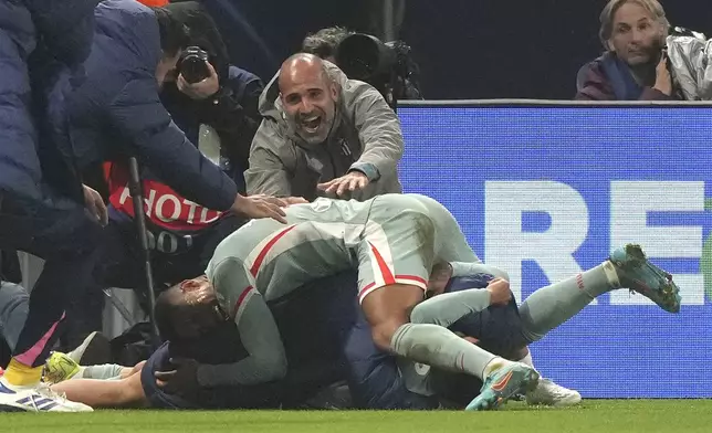 Atletico Madrid's Angel Correa, Below, celebrates with his teammates after scoring the second goal against PSG during the Champions League opening phase soccer match between Paris Saint Germain and Atletico Madrid, at the Parc des Princes stadium, in Paris, Wednesday, Nov. 6, 2024. (AP Photo/Michel Euler)