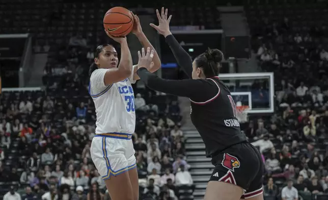 UCLA forward Timea Gardiner, left, tries a shot against Louisville's forward Elif Istanbulluoglu, right, during an NCAA college basketball game Monday, Nov. 4, 2024, in Paris, France. (AP Photo/Aurelien Morissard)