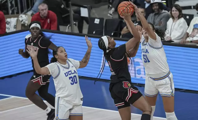 UCLA center Lauren Betts, right, blocks a shot by Louisville forward Nyla Harris, second from right, during an NCAA college basketball game Monday, Nov. 4, 2024, in Paris, France. (AP Photo/Aurelien Morissard)